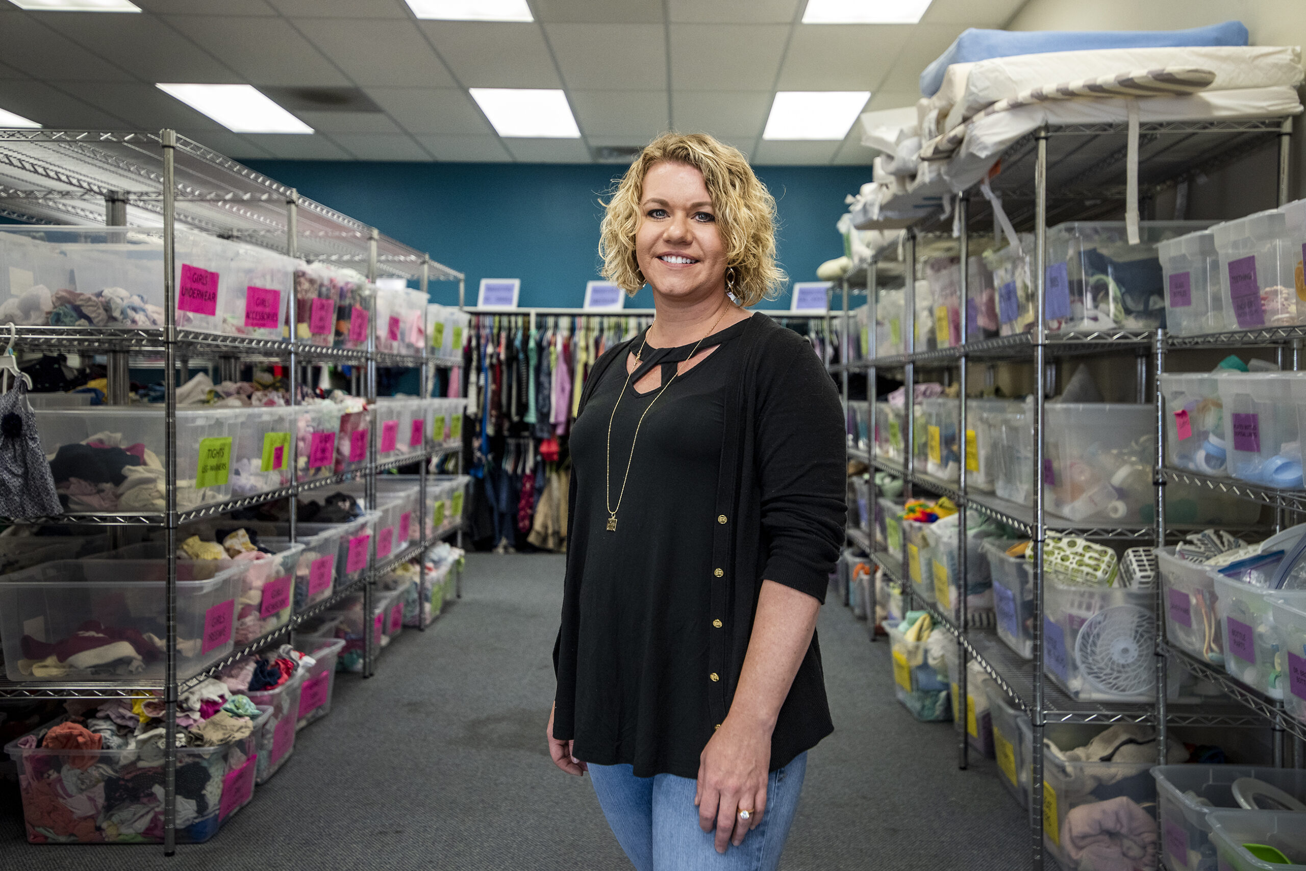A woman stands in a room filled with baby supplies.