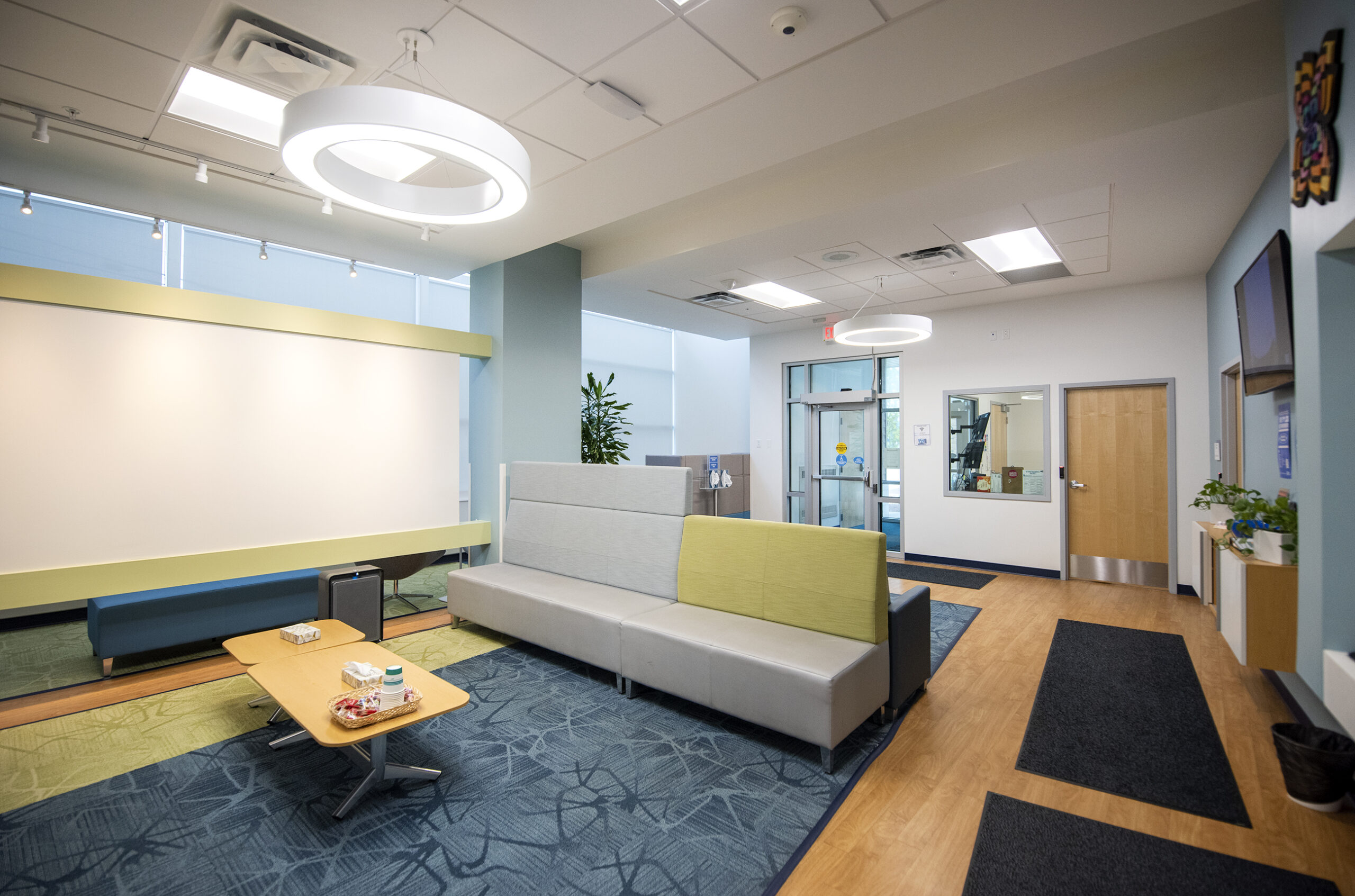 A lobby with seating and tables is decorated in green and blue.